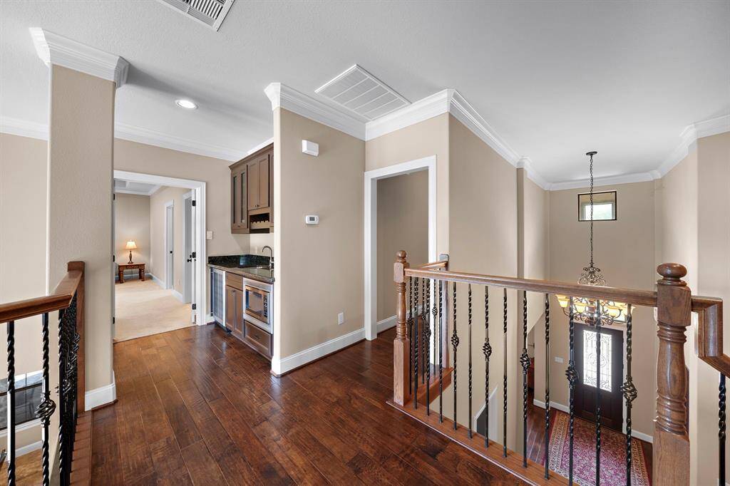 Located at the top of the stairs is a built-in wet bar and hallway leading to additional rooms, offering a spacious, welcoming atmosphere.