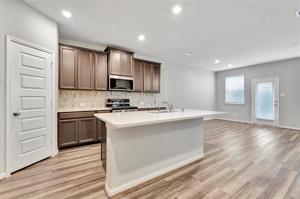 The expansive countertops, finished in light-colored stone provide ample room for meal prep, cooking, and even casual dining. The clean, expansive surfaces allow for both functionality and style, ensuring you have all the space you need for your kitchen tasks.