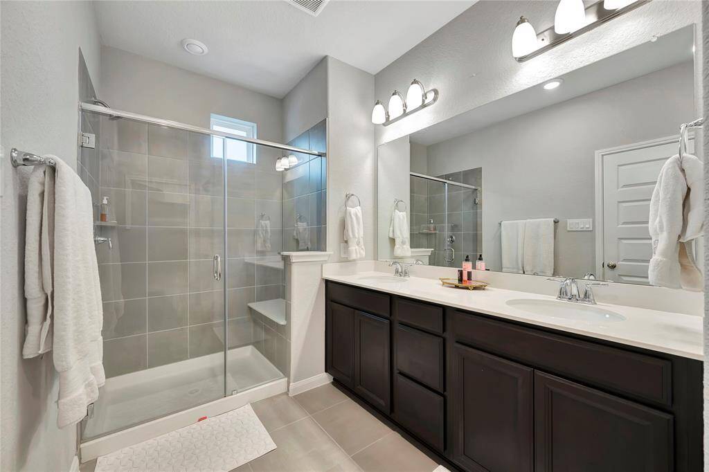 This elegant en suite bathroom is designed for both convenience and style, offering a sleek, stand-up shower as the focal point. The shower features contemporary fixtures, with a clean, minimalist design, making it perfect for quick, refreshing starts to your day or relaxing after a long one. The spacious shower is thoughtfully designed with modern tilework and a glass enclosure, ensuring both functionality and an open, airy feel.