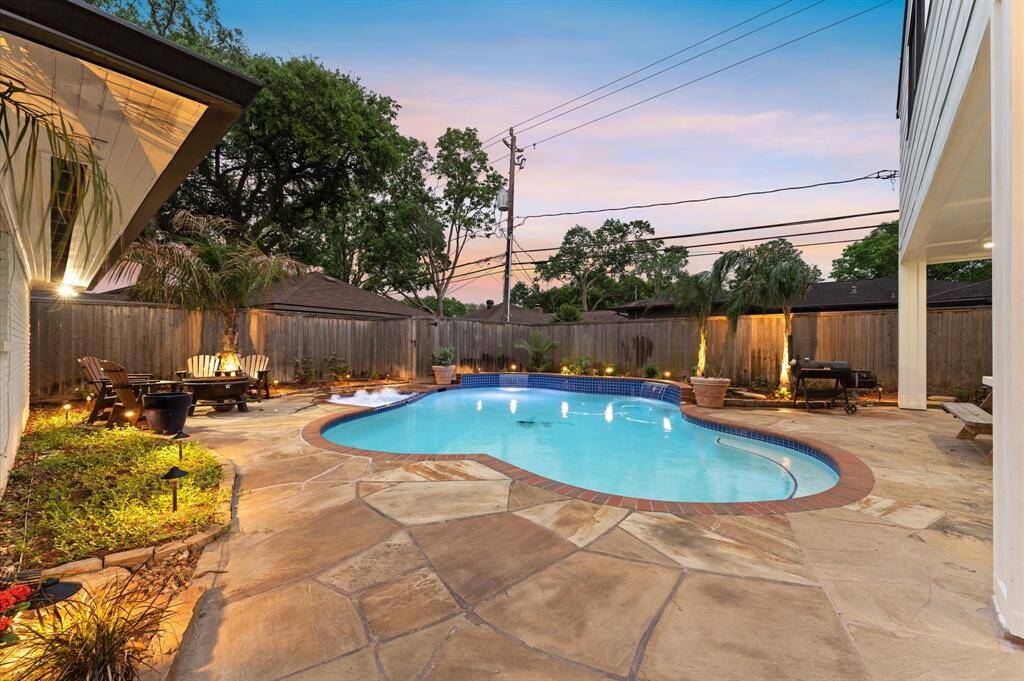 This inviting backyard features a beautifully curved pool surrounded by lush greenery and privacy fencing. Perfect for relaxation and entertaining.