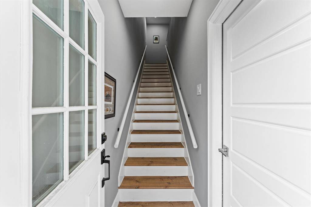 Bright, welcoming entryway to the garage apartment with a staircase leading up, featuring white walls and wooden steps. A glass-paneled door and a side door add a touch of elegance.Upstairs layout over the garage