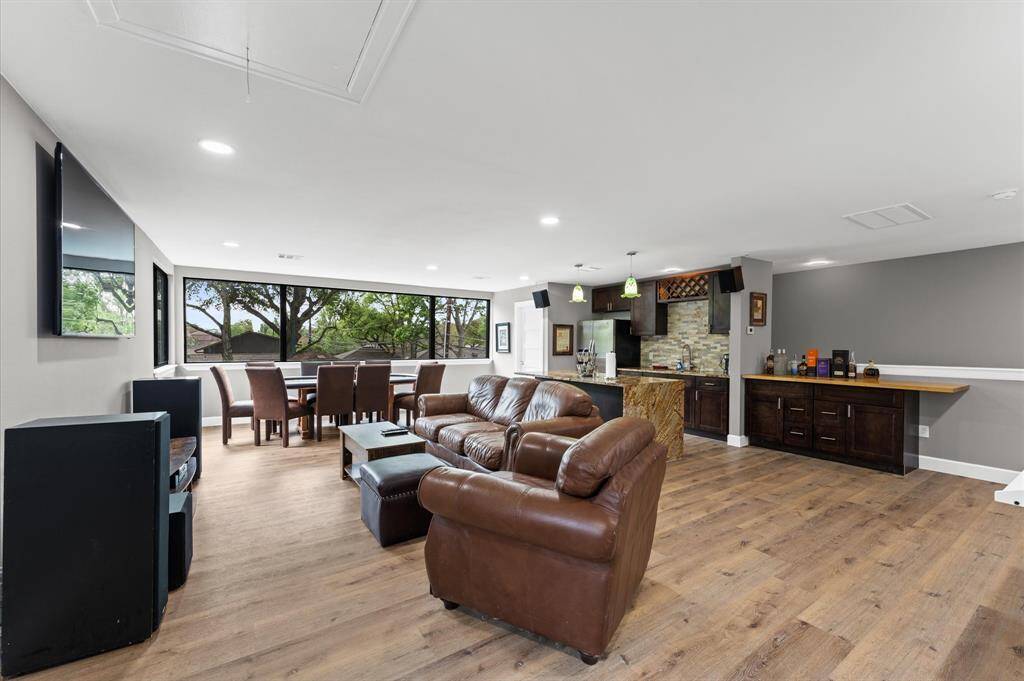 Open concept living area with hardwood floors, large windows offering abundant natural light, and a stylish kitchen island. Ideal for entertaining, with comfortable seating and a modern design.