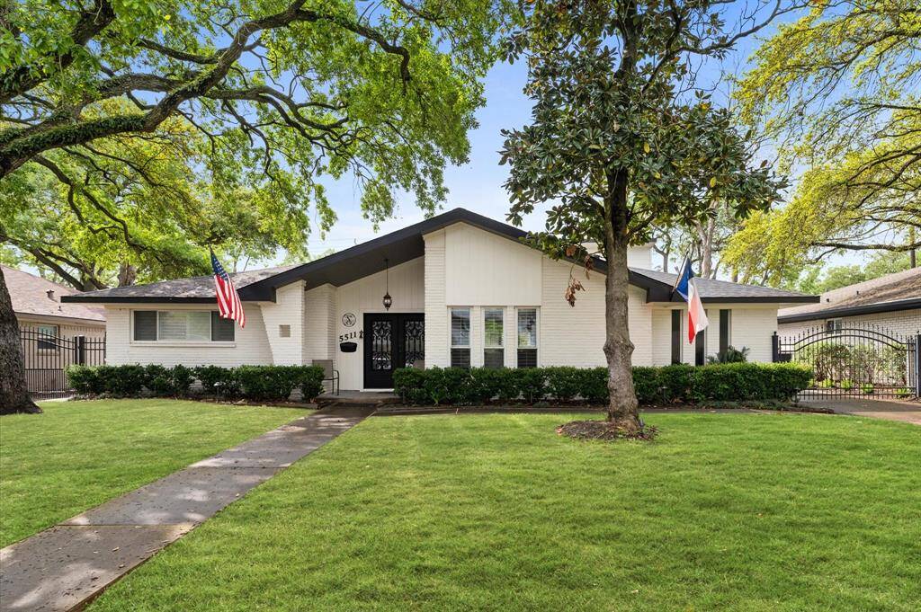 This lovely home features a welcoming courtyard with stone paving and tasteful landscaping. The exterior is well-lit, and the setting sun enhances the serene ambiance. The open space is ideal for outdoor dining or relaxation, framed by lush greenery.