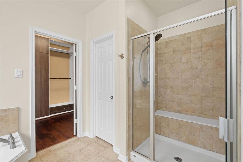 This spacious primary bathroom is a true retreat, featuring a relaxing jetted tub, convenient double sinks, a separate standing shower, and direct access to an incredibly spacious and upgraded closet.