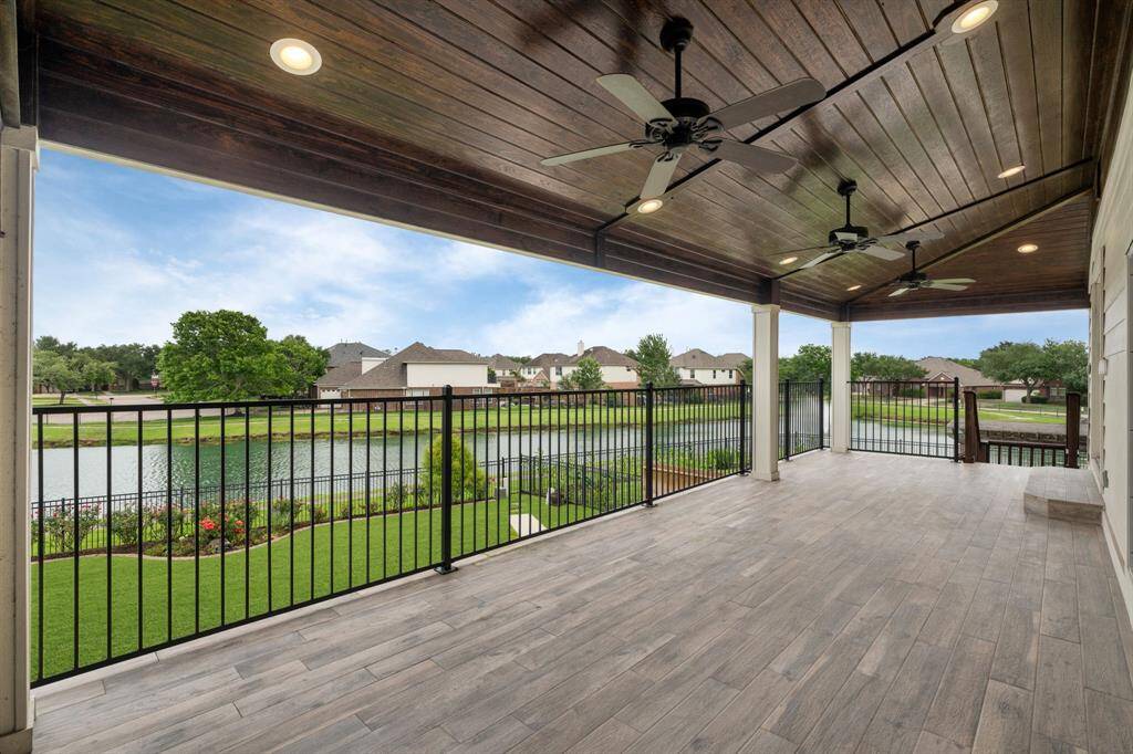 This inviting second-floor balcony offers a comfortable outdoor space with refreshing large fans and picturesque panoramas of the garden and the tranquil lake.