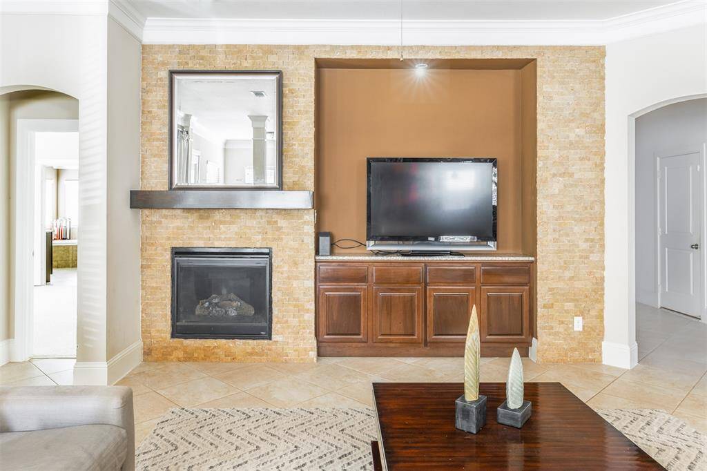 This stylish focal point features a floor-to-ceiling fireplace with stone surround, sleek mantle, and custom built-ins with granite countertops. It's a warm, elegant backdrop for cozy nights or relaxed entertaining.