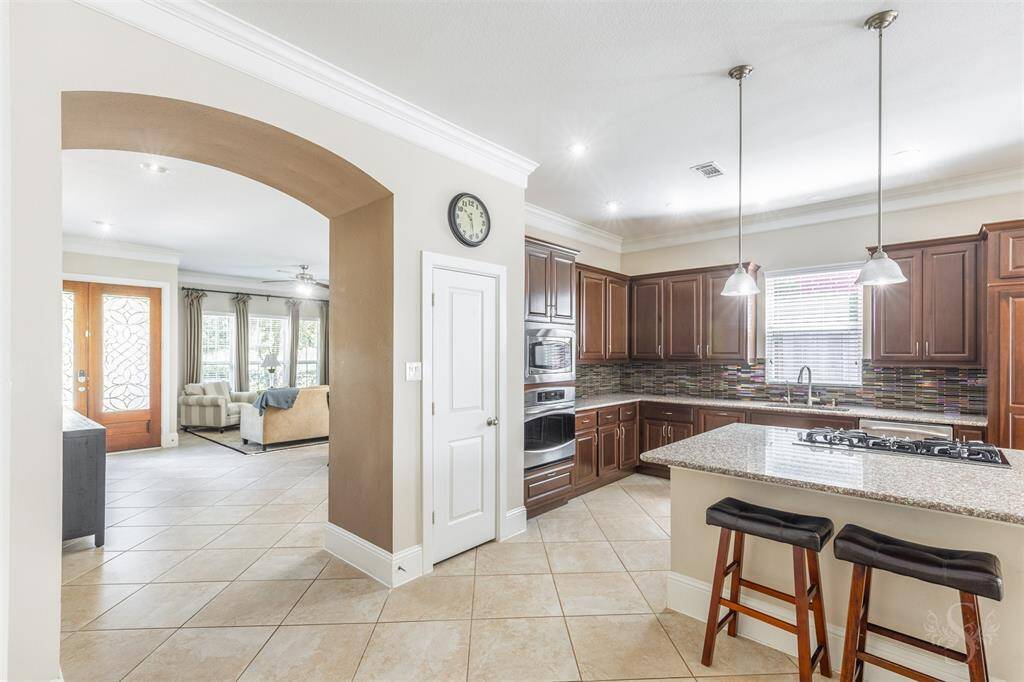 An arched entry welcomes you into the gourmet kitchen, where a granite island under pendant lighting, stainless steel appliances, and abundant prep space combine in an ideal layout.