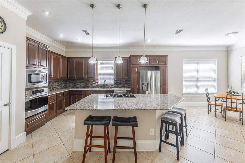 Welcome to the gourmet kitchen featuring granite counters and large granite island, rich cabinetry, stylish backsplash, stainless steel appliances and gas cooktop! There's plenty of room for more than one chef in this kitchen!