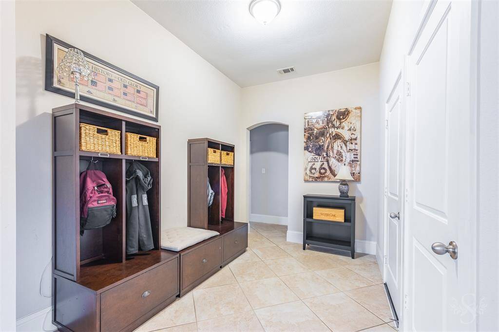This spacious hallway offers a versatile drop zone near the garage entrance, ideal for organizing daily essentials. Tile flooring and arched entryways add to the home's clean, cohesive design.