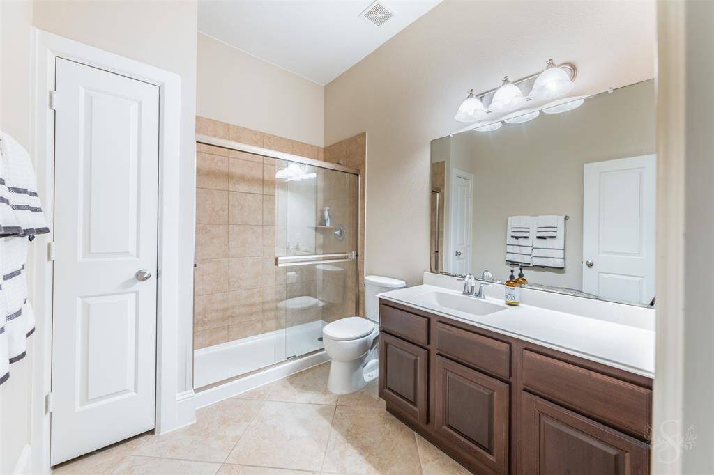 A well-appointed secondary full bath includes an extended vanity and an enclosed shower with tile surround.