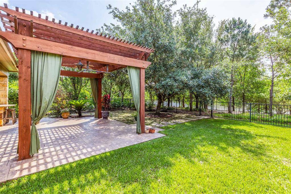 Enjoy the perfect blend of sunlight and shade under the wood pergola, surrounded by greenery and mature landscaping. The backyard feels like a private retreat with ample room to unwind or entertain.