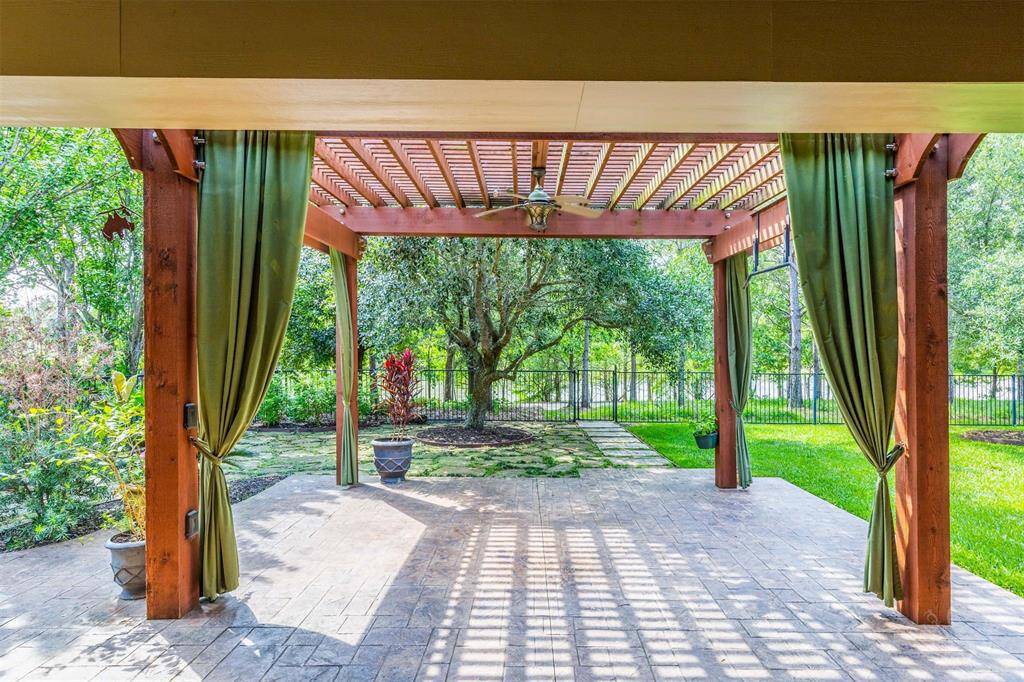 Step out under the pergola and enjoy a tranquil view of mature trees and a peaceful lake just beyond the wrought iron fence. The stamped patio extends into a lush lawn, offering a seamless blend of outdoor living and natural beauty. Imagine yourself sitting here enjoying this amazine view!