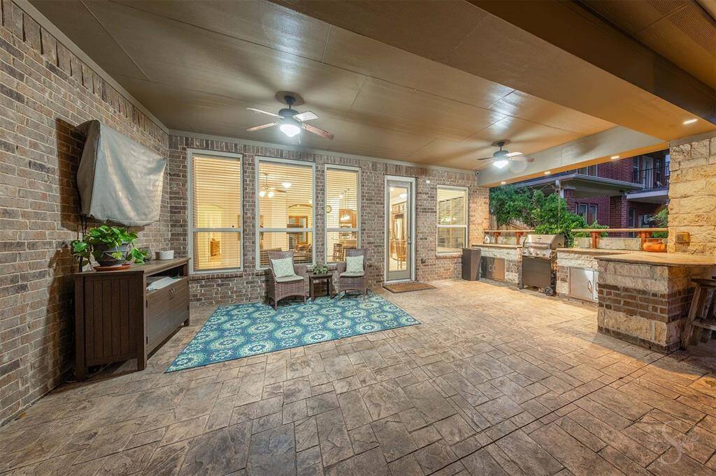 This spacious covered patio offers a comfortable extension of the home with dual ceiling fans, durable stamped concrete, and ample room for outdoor seating. The built-in stone outdoor kitchen with grill makes it easy to host gatherings and enjoy open-air dining in style.