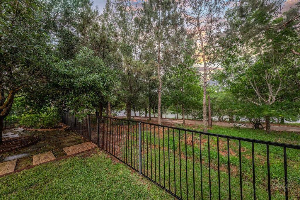 As the sun sets, the tranquil lake and wooded trail beyond the iron fence create a peaceful and private backdrop - perfect for winding down or hosting a quiet evening gathering.