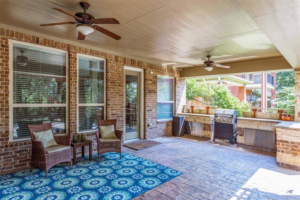 The covered patio features lighted ceiling fans and a built-in outdoor kitchen with a grill and stone surround - perfect for weekend cookouts. There's ample space for both lounging and dining while enjoying views of the backyard and lake!