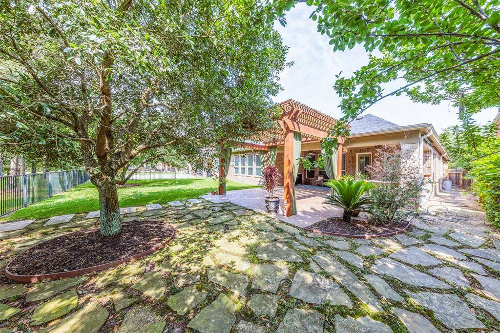 Enjoy tranquil lakefront living in this beautifully landscaped backyard, complete with a wrought iron fence and mature shade trees. The expansive stamped concrete patio with pergola, ceiling fan, and outdoor kitchen creates the ideal setting for entertaining or relaxing in your private sanctuary.