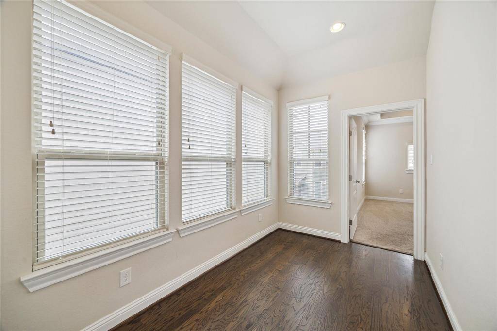Cozy hallway with hardwood floors and large windows with blinds, leading to Primary Bedroom. Ideal for a reading nook or study area.