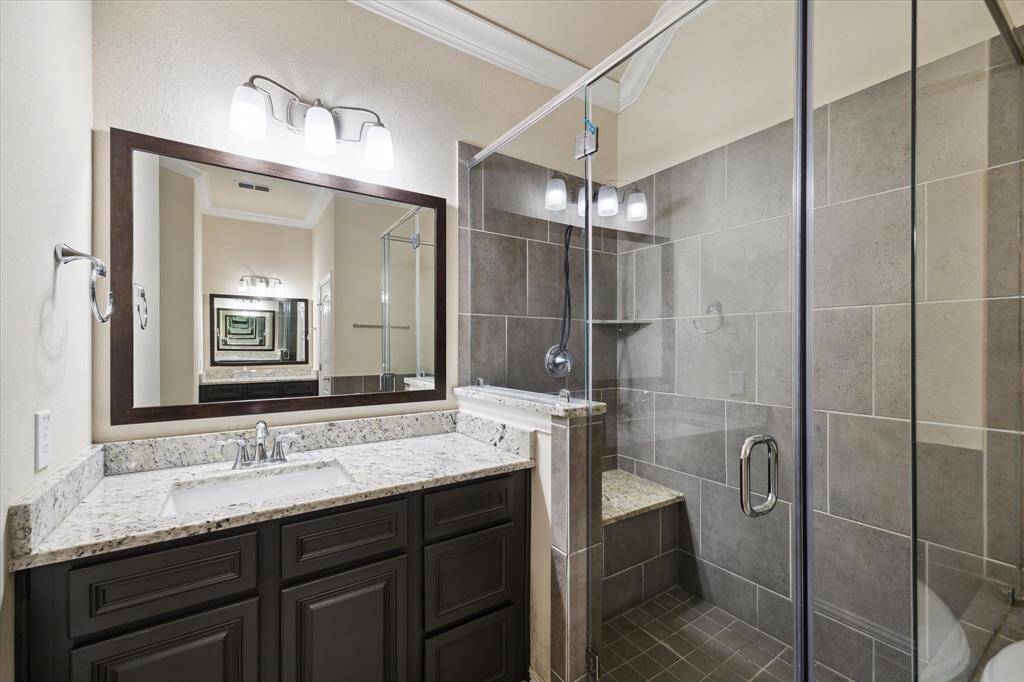 Primary bathroom features a modern design with a glass-enclosed shower, large mirror, and granite countertop. The neutral tile work and dark wood vanity add a touch of elegance.