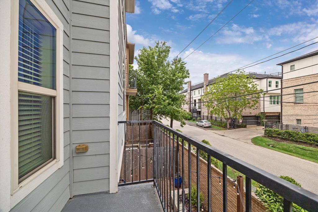 Cozy balcony view showcasing a quiet residential street with modern townhomes, greenery, and ample natural light.