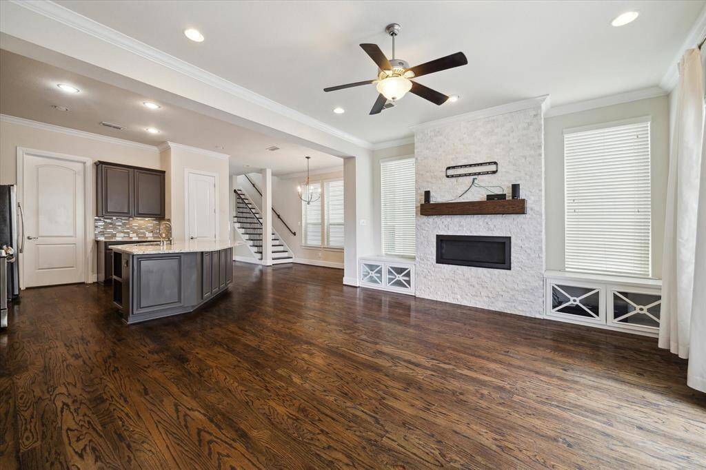 Open-concept living area with rich hardwood floors, a modern kitchen featuring a central island and stainless steel appliances, and a cozy living space with a sleek fireplace and abundant natural light.