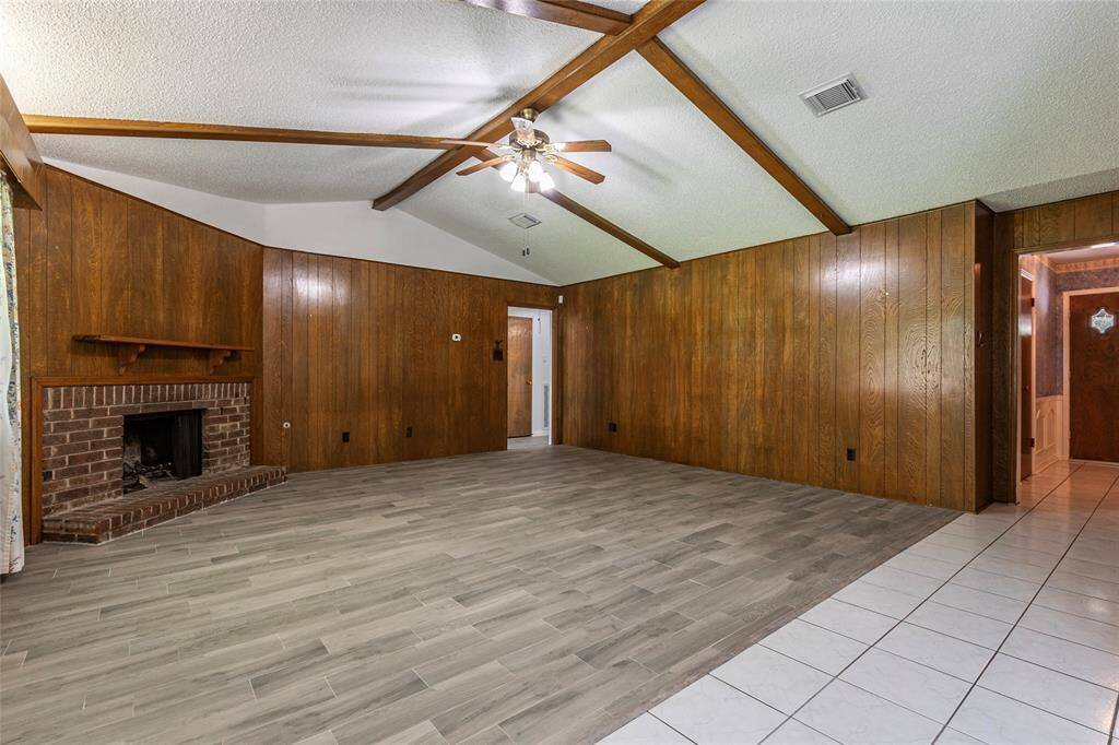 Step into the spacious living room featuring exposed wood beams and a cozy gas fireplace, offering warmth and character.