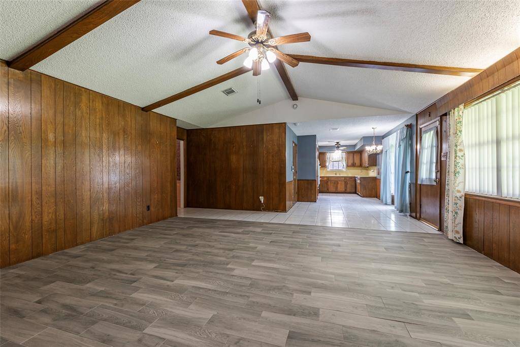 Spacious living room with gas fireplace, rich wood beams, and updated flooring.