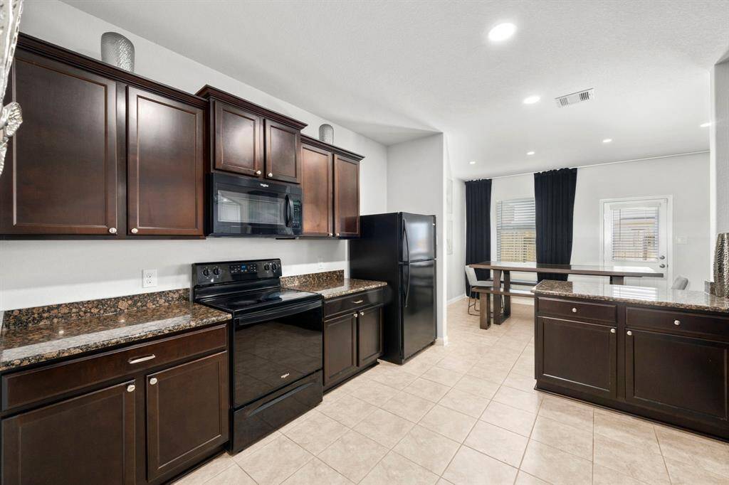 Large kitchen with dark wood cabinets and countertops