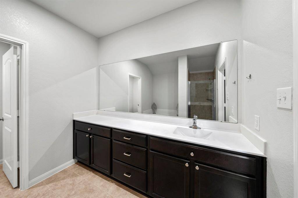 Large primary bathroom has plenty of counter space and same beautiful mahogany cabinets.