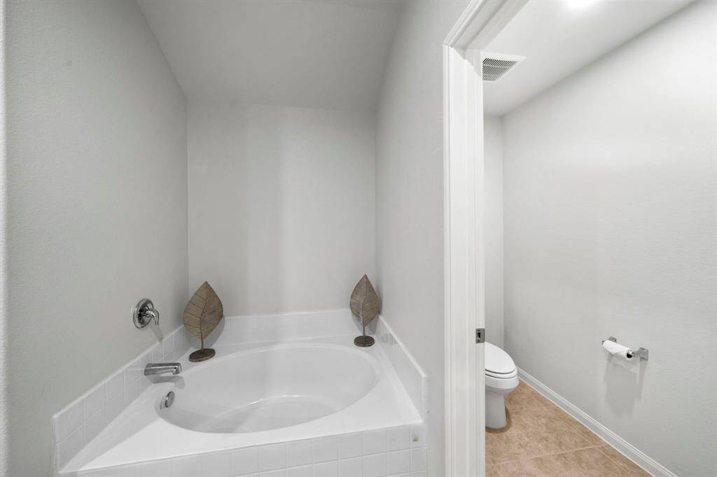Large soaking tub and water closet with privacy door.