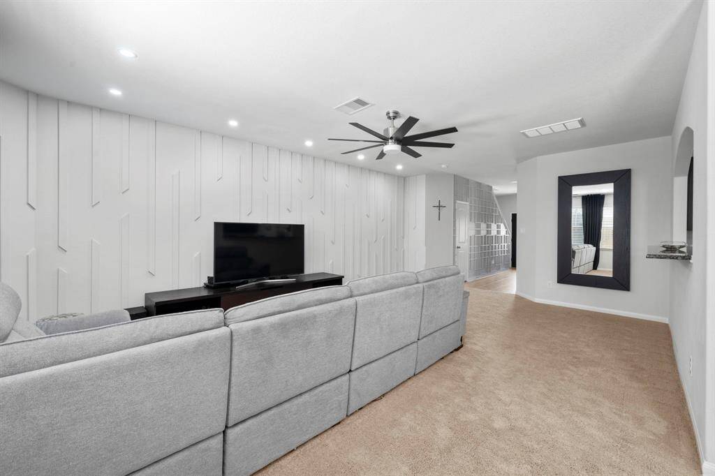 Another custom accent wall with modern ceiling fan/recessed lighting and bar top area to see through kitchen.