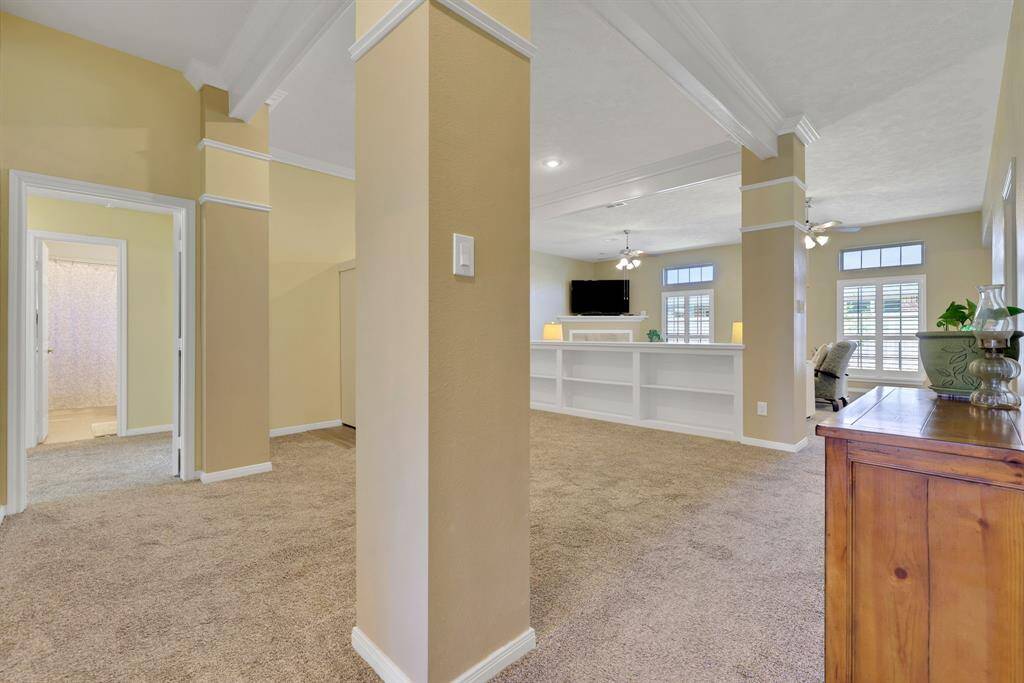Large open area next to living room with custom built-ins, decorative columns, trayed ceilings, and crown molding. Ask about sellers carpet adjustment :)