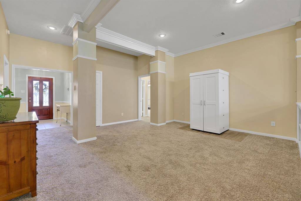 Large open area next to living room with decorative columns, trayed ceilings, and crown molding.