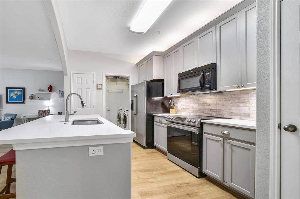 kitchen updates include new oven/cooktop and quartz countertops. Can see a view into the laundry room, large enough for side-by-side washer/dryer and more storage.