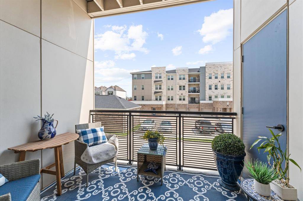 Enjoy fresh air and morning coffee from your covered balcony—complete with decorative flooring, cozy seating, and a peaceful courtyard view.