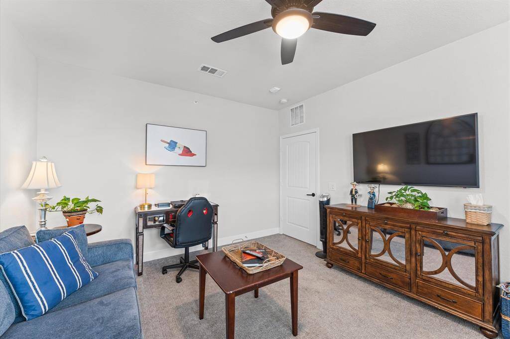 Currently set up as a home office and den, this multi-purpose room offers space for a large TV, ample storage, and comfort for work or leisure.