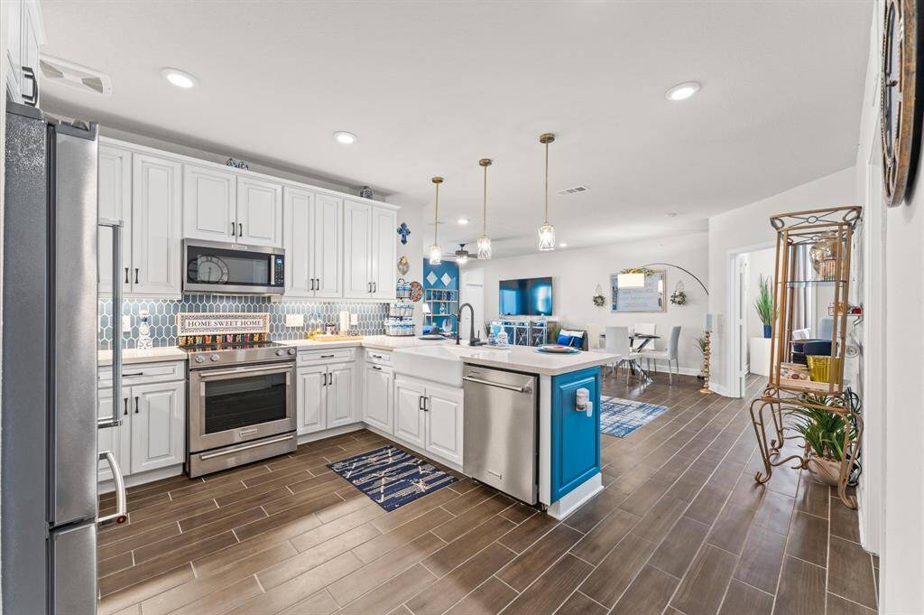 A seamless layout extends from the gourmet kitchen into the dining area, offering beautiful pendant lighting and luxury flooring.