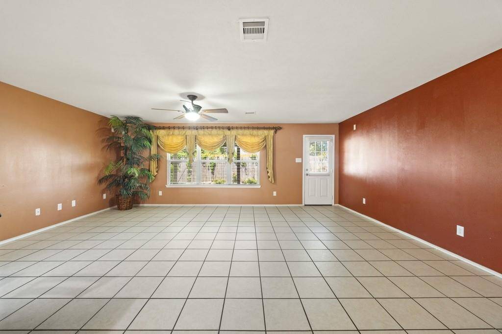 Large main living room with backyard access and tile floors.