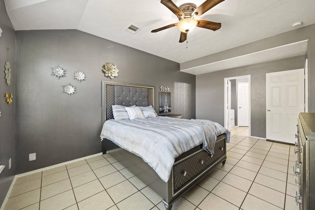 Another view of the primary bedroom with neutral tones and tile flooring.