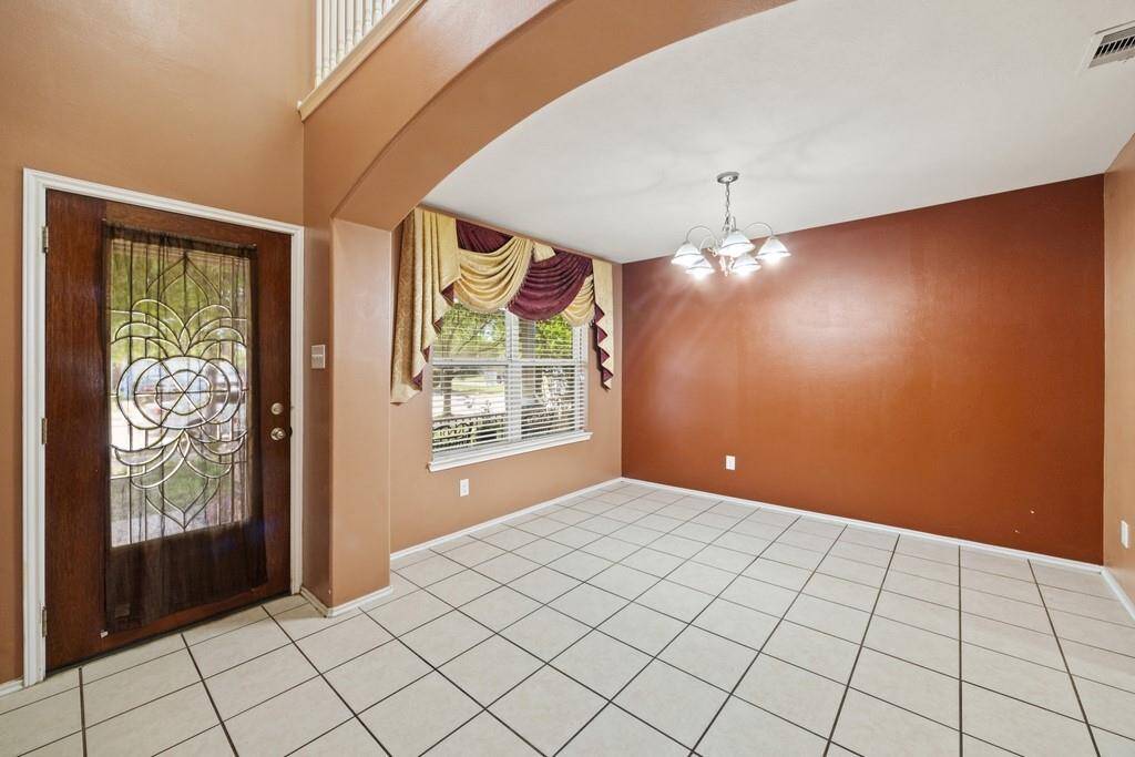 Formal dining room with tile flooring and large windows.