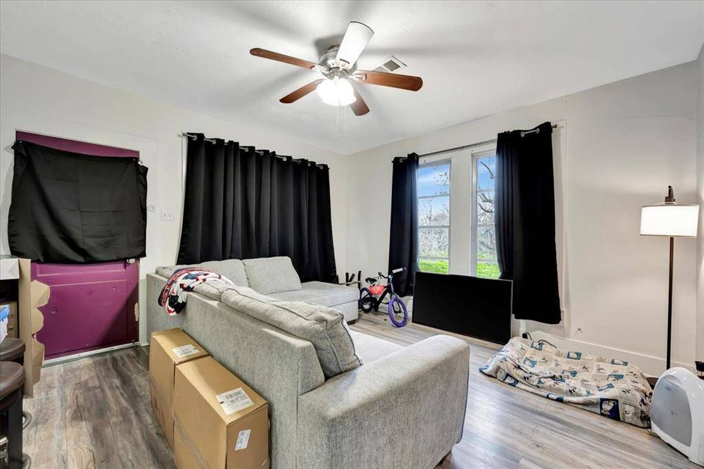 Bright living room with multiple windows and vinyl floors.