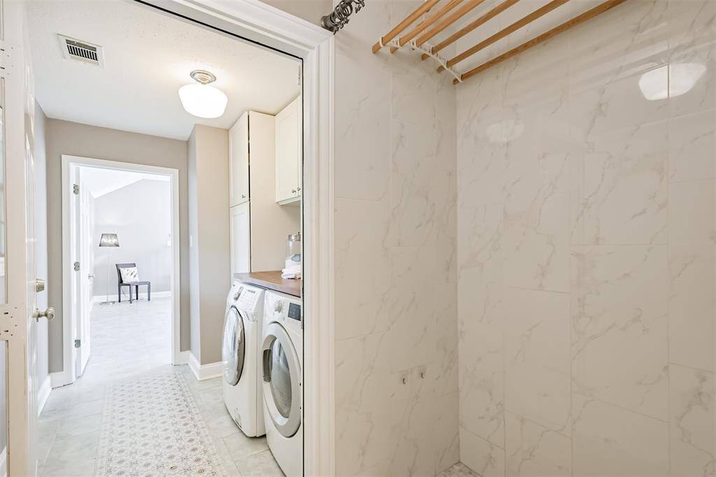 Lovely tiled floors flow seamlessly from the garage entrance through to the family room, making it easy to transition from outdoor fun to indoor relaxation. With the laundry room conveniently located next to entrances from both the back door and garage, cleaning up after a day outside has never been easier.  This photo also shows a shower, complete with handheld wand, which is perfect for bathing after taking a dip in the pool or even washing a pet before allowing them back into the house!