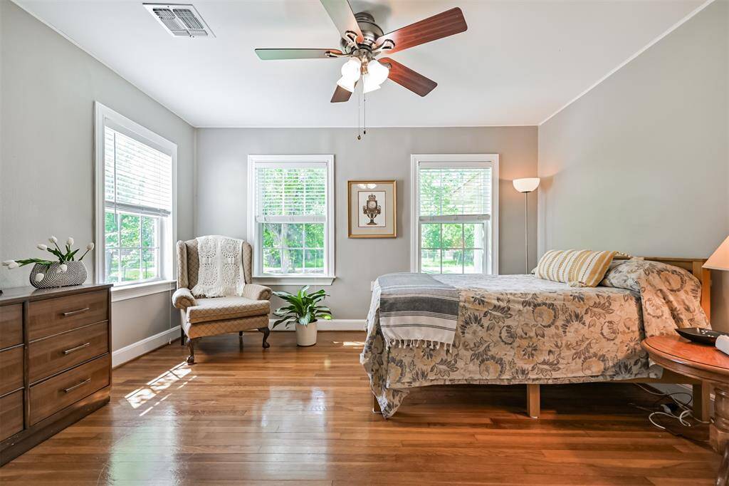 This charming bedroom, one of three located in the original 1938 part of the home, features gleaming hardwood floors, beautiful windows that let in natural light, and a ceiling fan for comfort—a peaceful retreat full of character.