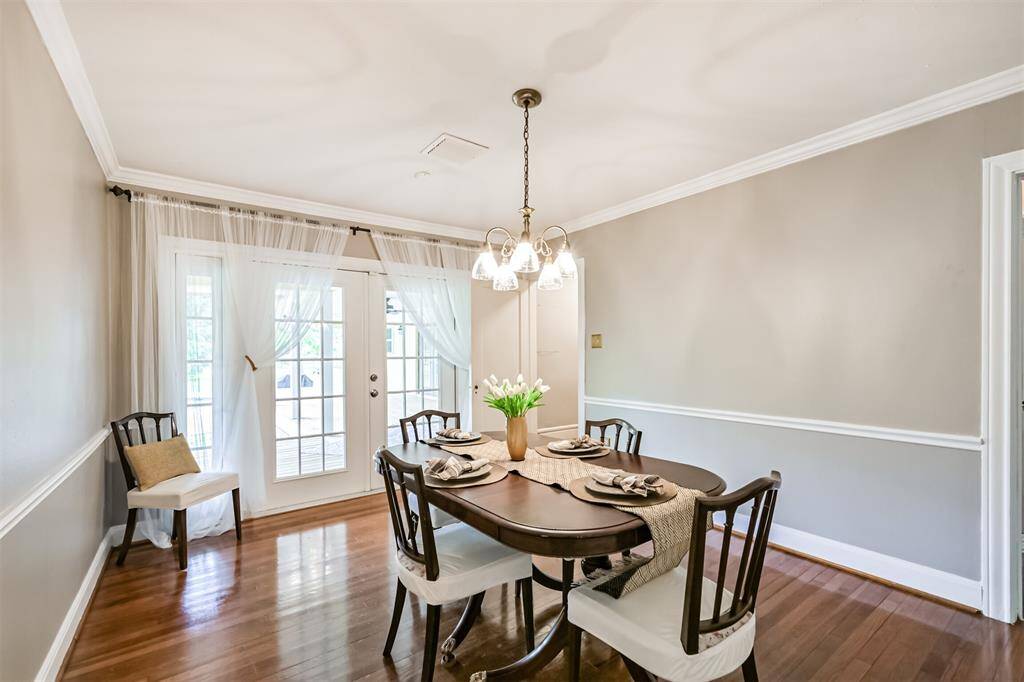 This inviting dining room features warm wood floors and elegant French doors that open to a stunning covered back porch—perfect for seamless indoor-outdoor entertaining.