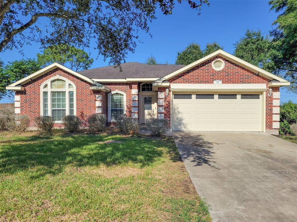 Charming brick home with a two-car garage and a well-maintained front yard. Features large arched windows and a cozy entryway, surrounded by mature trees for added privacy.