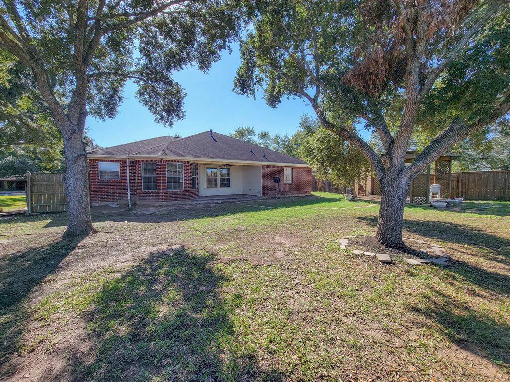You're looking at a single-story brick home featuring a spacious backyard with mature trees and a privacy fence, offering a blend of shade and open space for outdoor activities.