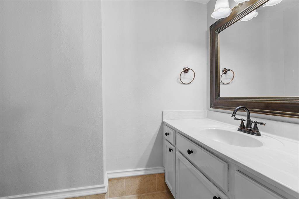 Take a look at your downstairs half bathroom, a stylish and functional space. The sleek white vanity offers ample storage to keep essentials organized, while a large framed mirror enhances the sense of space. Modern fixtures add a contemporary touch, and its convenient location makes it perfect for guests, providing a fresh and inviting feel.