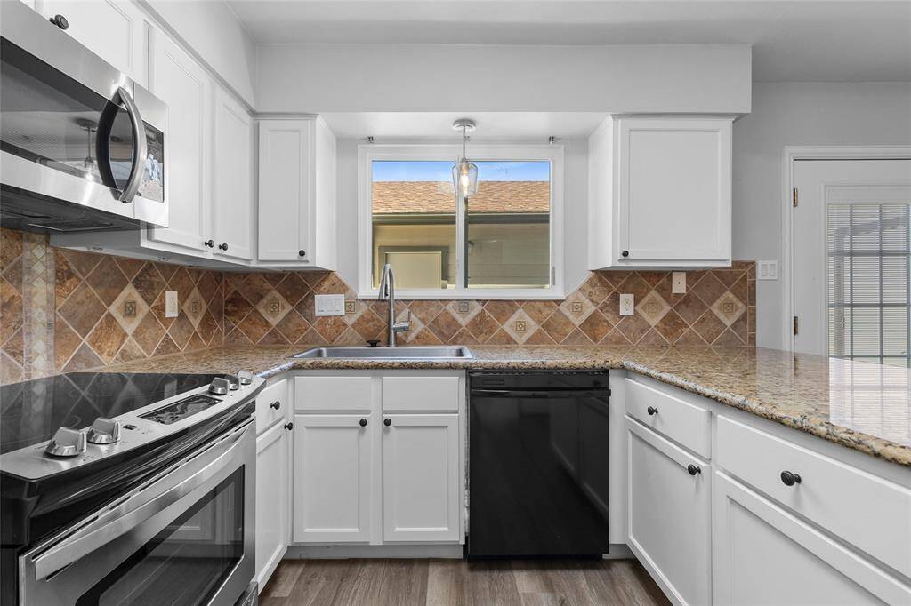 Your kitchen features modern stainless steel appliances, crisp white cabinetry, and sleek granite countertops. A tile backsplash adds texture and style, while the window above the sink fills the space with natural light.