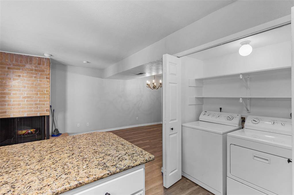 This photo showcases your laundry area, conveniently located right behind the kitchen. It offers space for a full-size washer and dryer, along with plenty of shelving for storage. Bi-fold doors provide easy access, and a light brightens the space, making it both practical and functional.