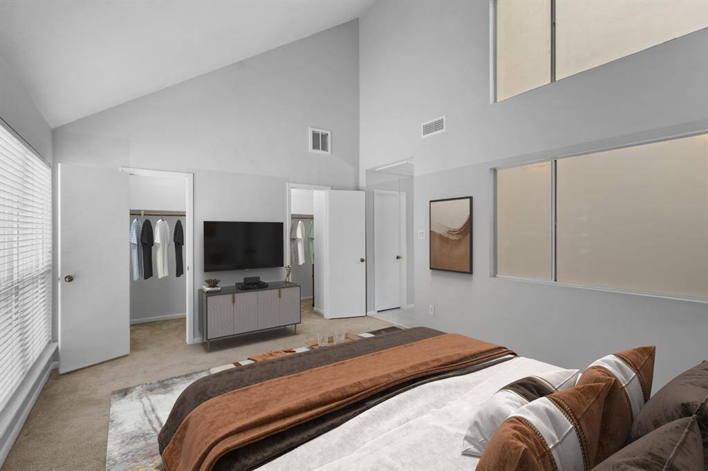 Another look at your primary bedroom reveals high ceilings and large windows that bathe the room in natural light. Two spacious closets offer plenty of storage, while the neutral color palette enhances the serene and welcoming vibe.