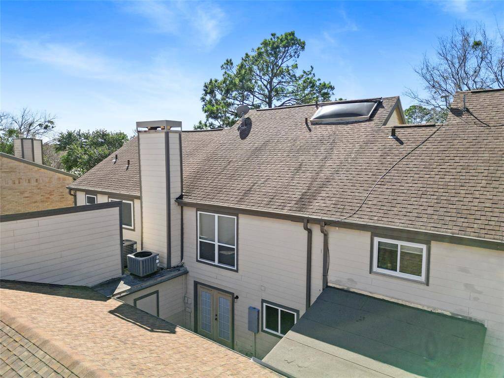 This photo shows the back exterior of your two-story townhouse with a gabled roof. The house features light-toned siding and large windows, surrounded by trees, offering a private and serene setting.